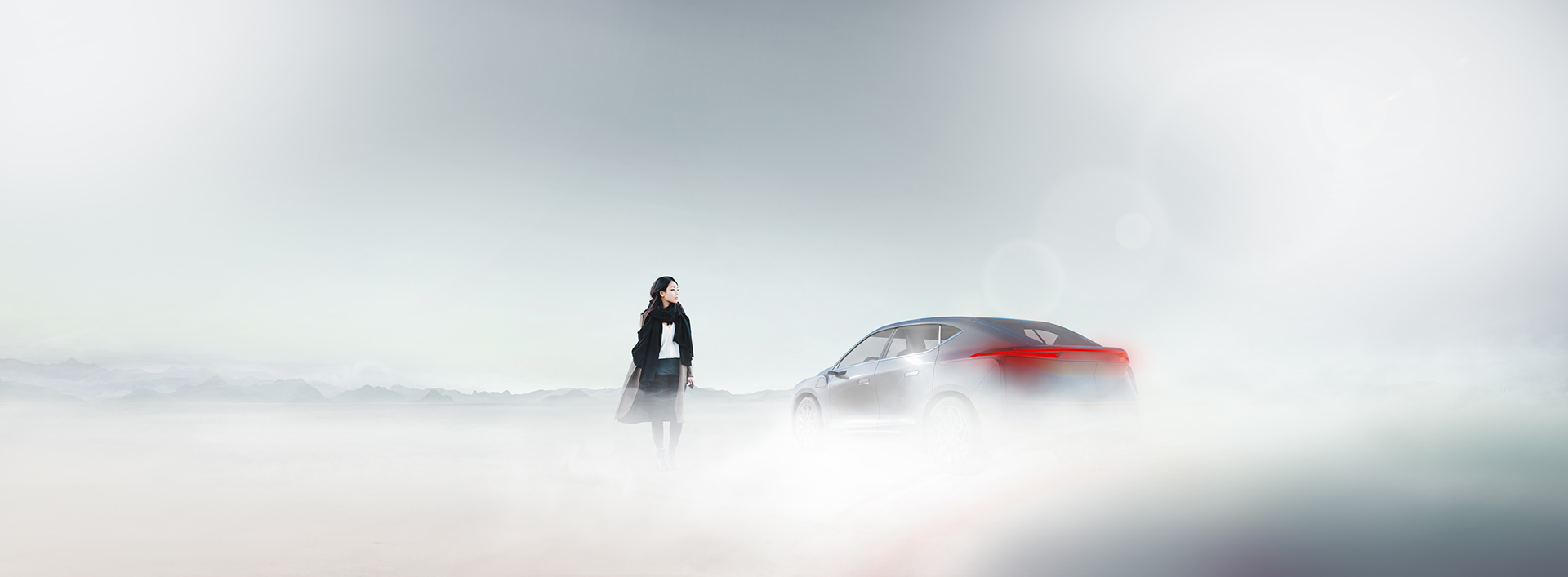 Person walking away from a vehicle in the fog with mountain range in the distant horizon