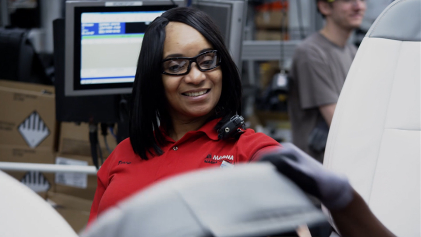 Person smiling and working in a manufacturing facility
