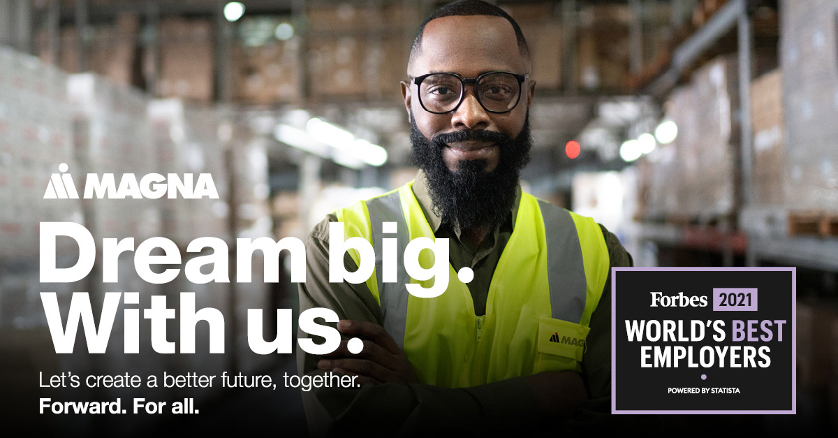 Person with arms crossed standing in a factory with recruiting messaging for Magna