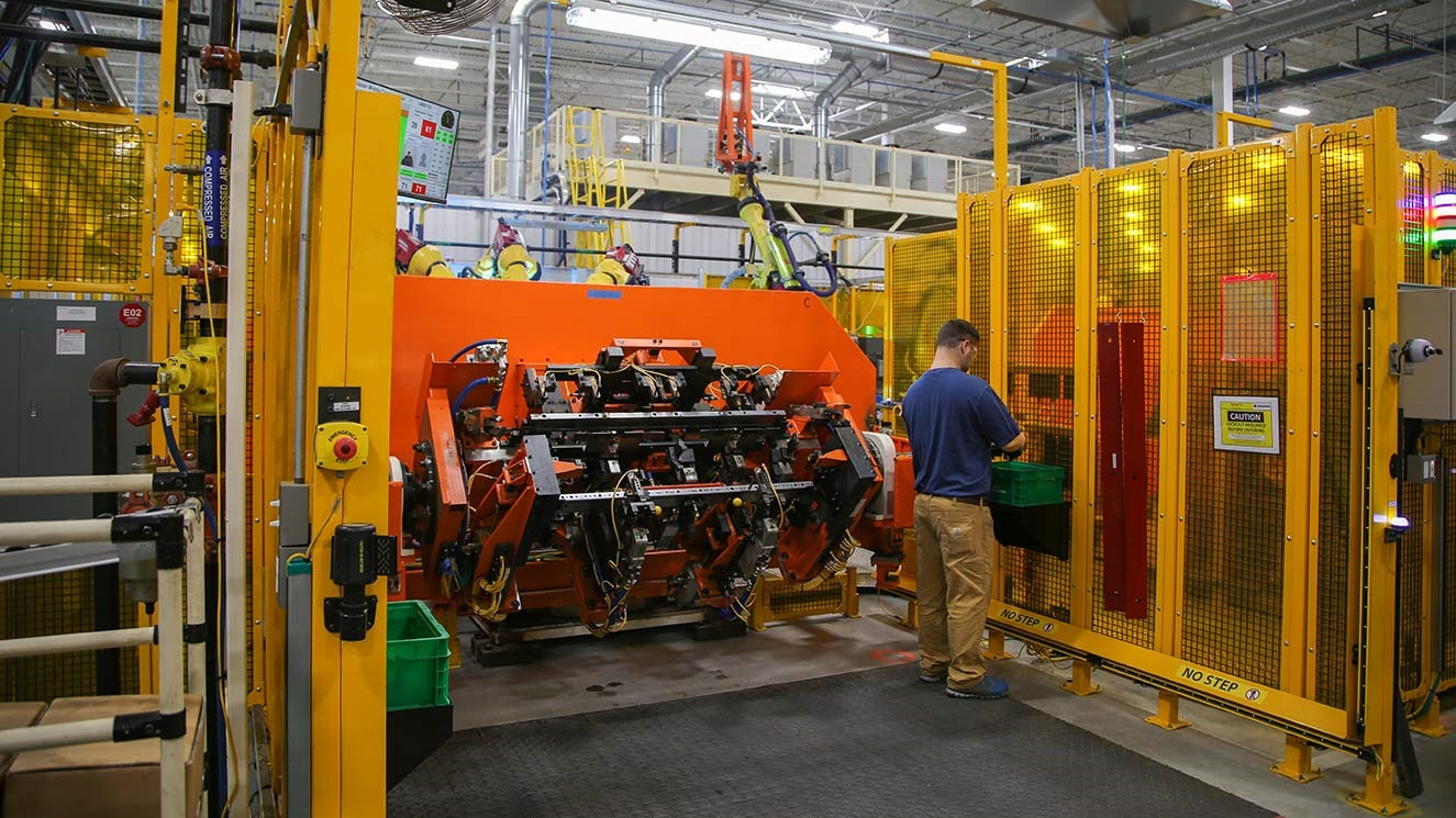 Person working on a machine in an automotive parts manufacturing facility
