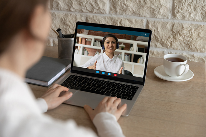 A person talking to a person on a laptop conducting a job interview virtually.