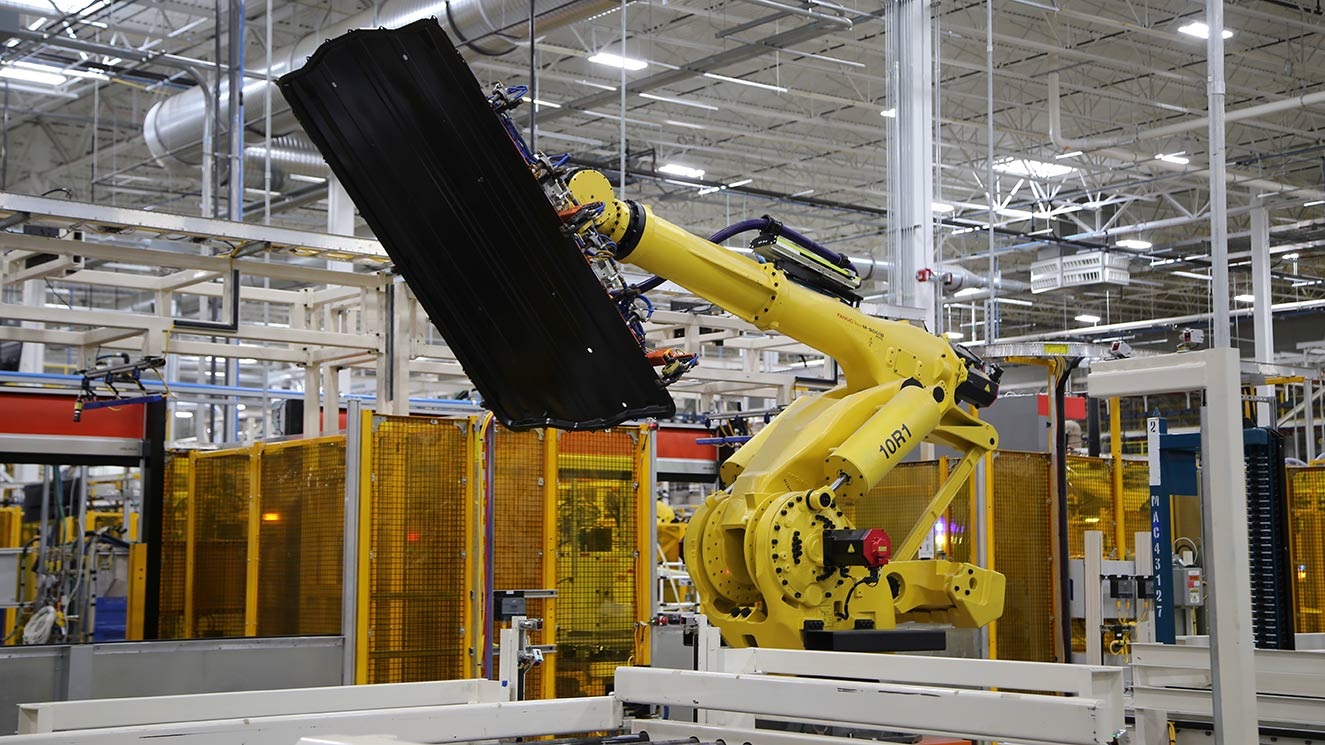 Robot picking up battery tray in manufacturing facility