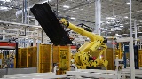 Robot picking up battery tray in manufacturing facility