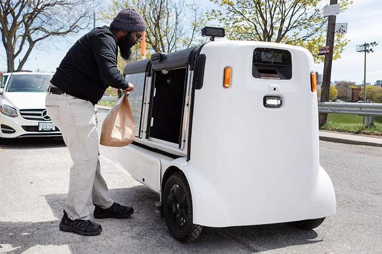 Person putting a bag into a delivery bot