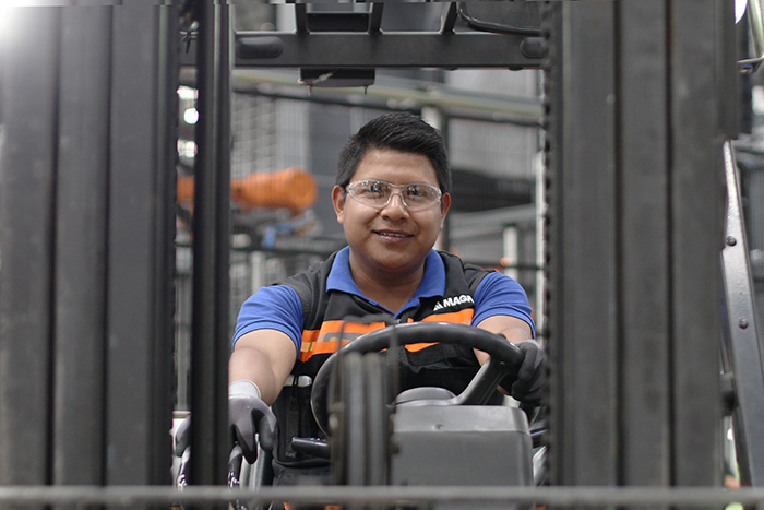 An employee smiling while being in a lift truck