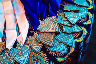 Rebelle Rally participation medals with blue and pink ribbons displayed on a table