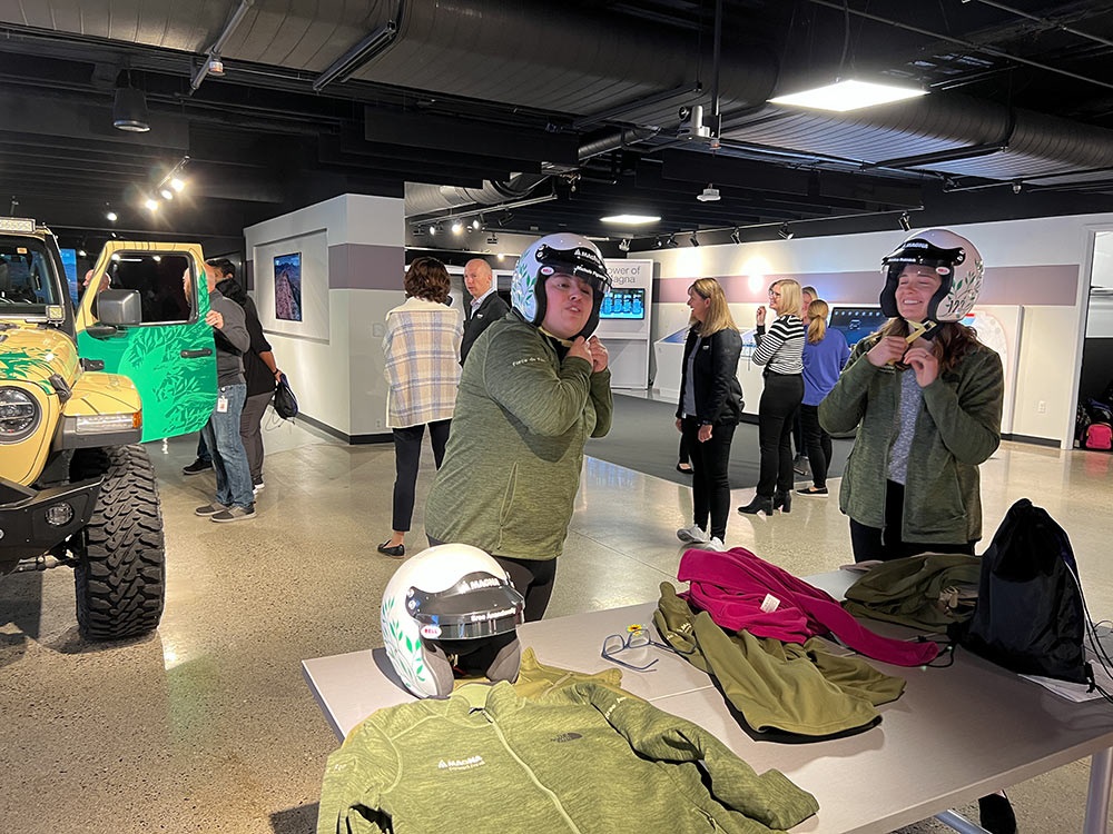 People with in room with Jeep® Gladiator Rubicon with two people trying on helmets