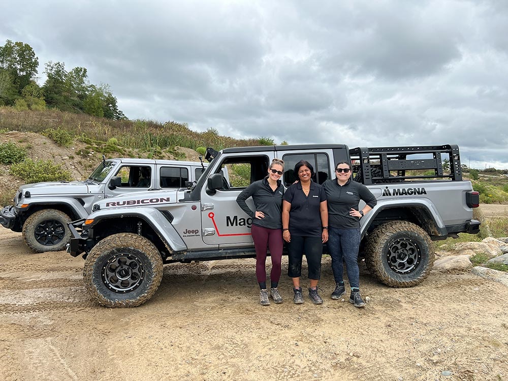 Three people standing outside of a Jeep® Gladiator Rubicon on rugged terrain