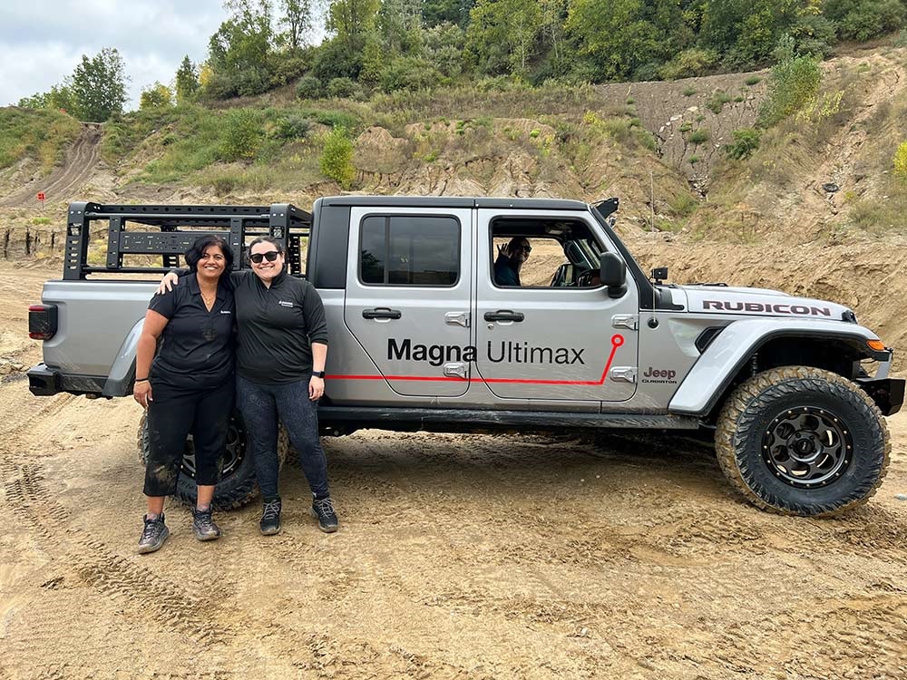 Two people standing outside of a Jeep® Gladiator Rubicon in rugged terrain