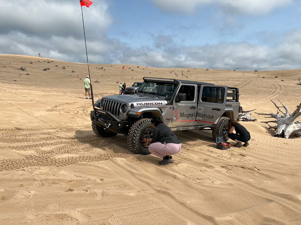 Two people changing tires on Jeep® Gladiator Rubicon in rugged terrain