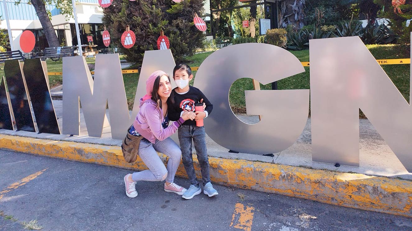 Miriam Montiel Martinez with her son standing in front of a Magna sign