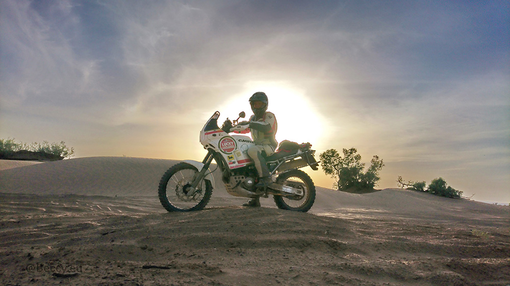 Rebecca Kleis on motorcycle in the desert with sun setting in the background.
