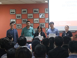 Group of standing together with three people in the middle holding certificates