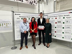 Group of standing together with a person in the middle holding a certificate