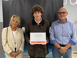 Three people standing together with the person in the middle holding a certificate