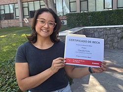 Person standing in front of a building holding a certificate