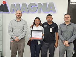 Group of standing together in front of the Magna logo with two people in the middle holding a certificate
