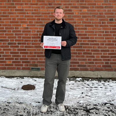 Edvin Hoog holding the Don Walker Scholarship Program Award