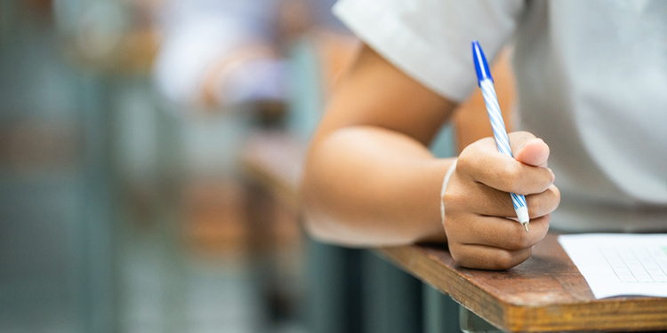 Person sitting at a desk and holding a pen