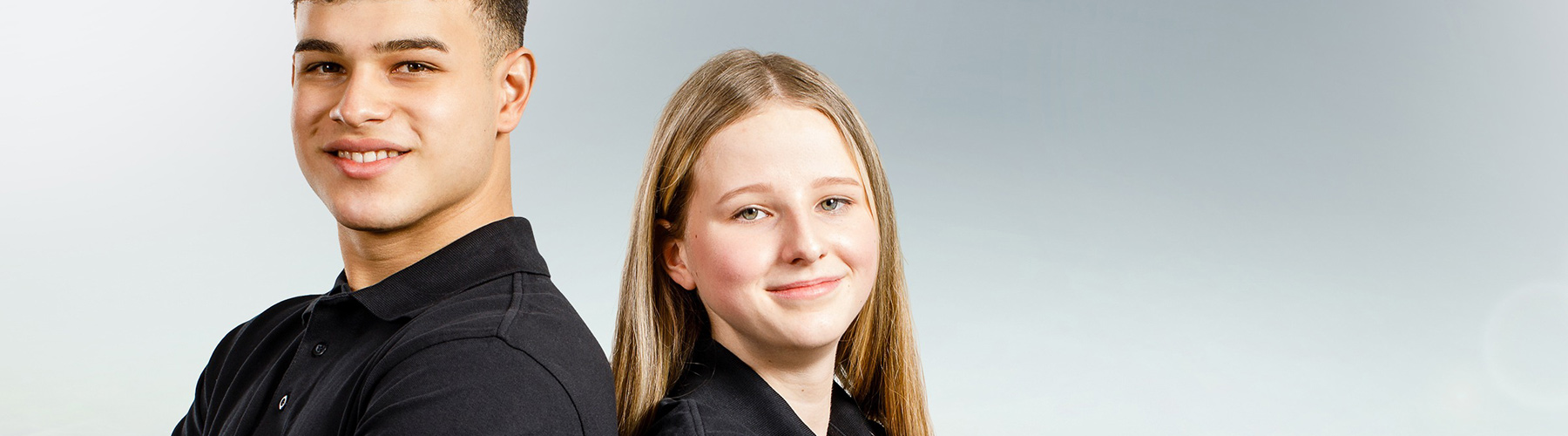 Close up of two people standing back to back and smiling