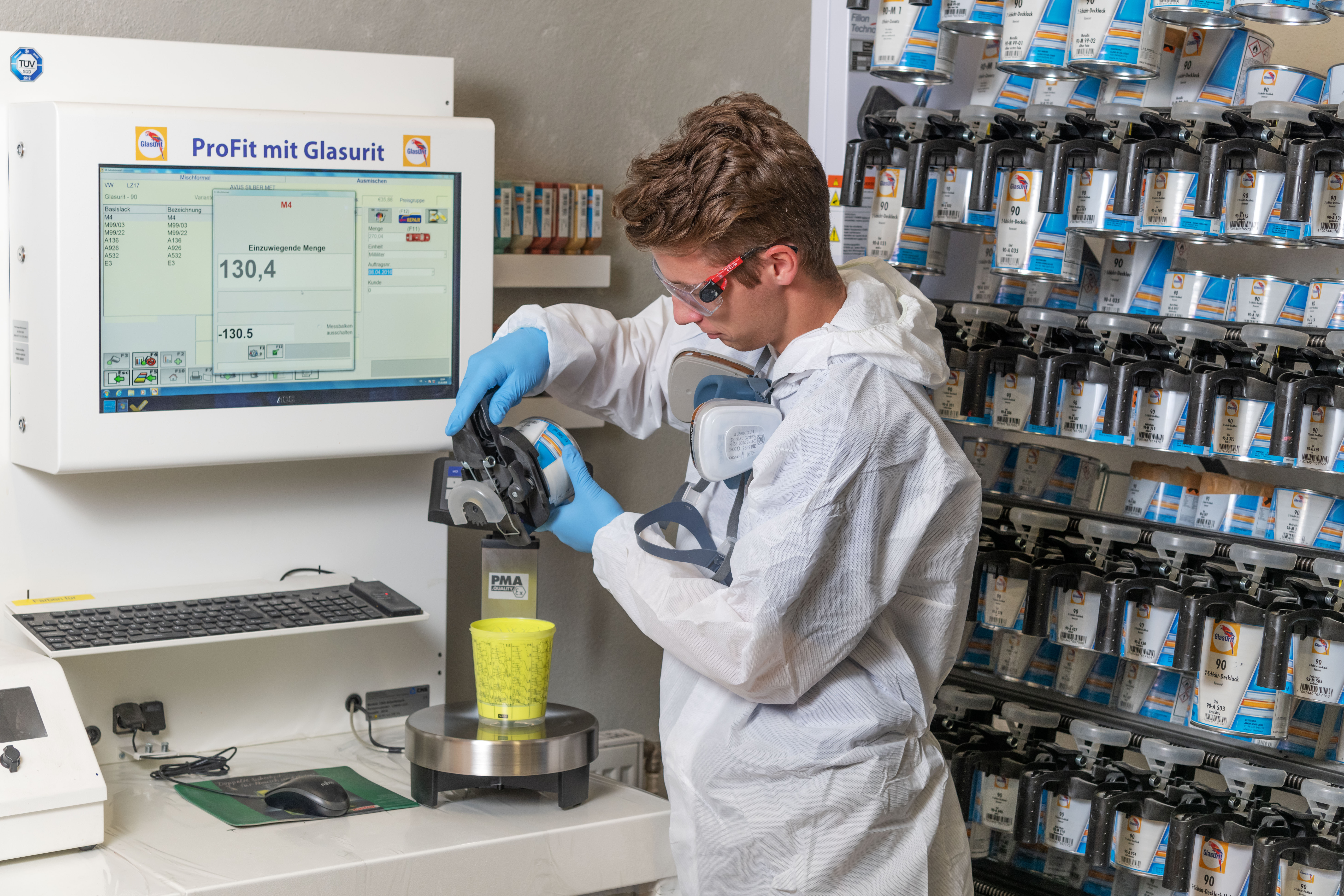 Technician in protective gear mixing paint in a laboratory