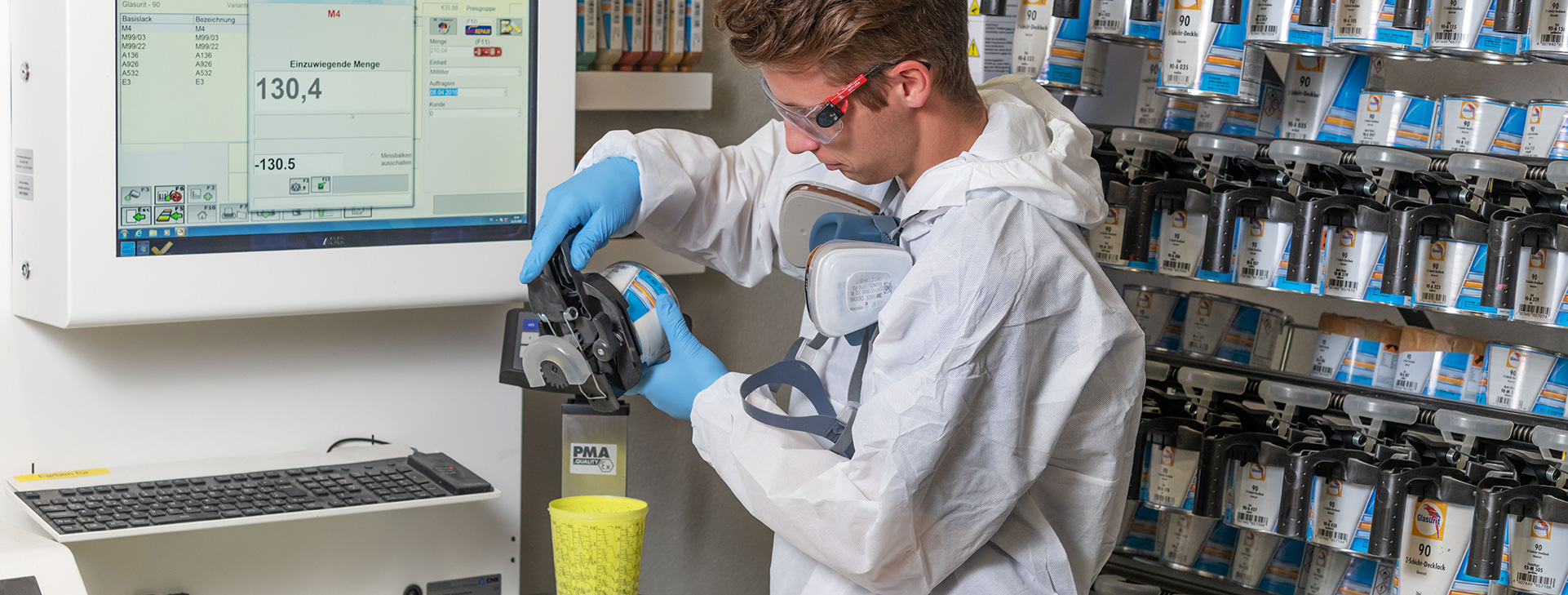 Worker in protective gear mixing paint using a dispensing machine