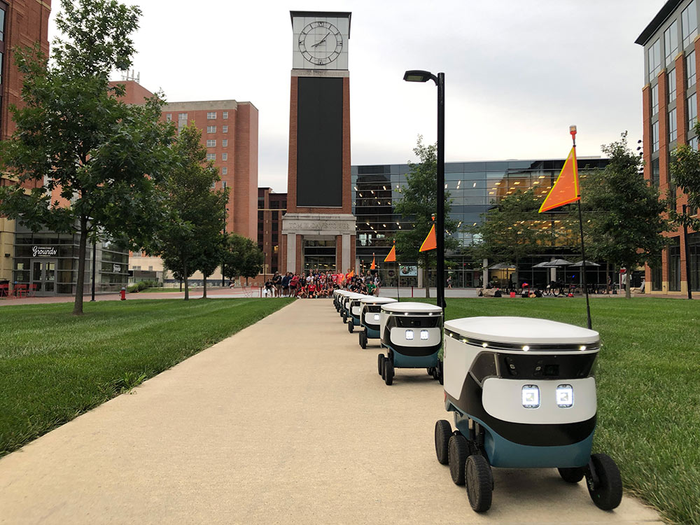 Two people standing in front of a building with electric two-wheelers.