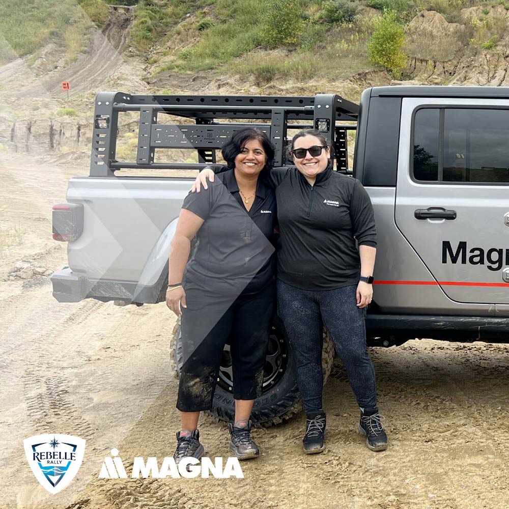 Two people standing outside of a Jeep Rubicon in rugged terrain