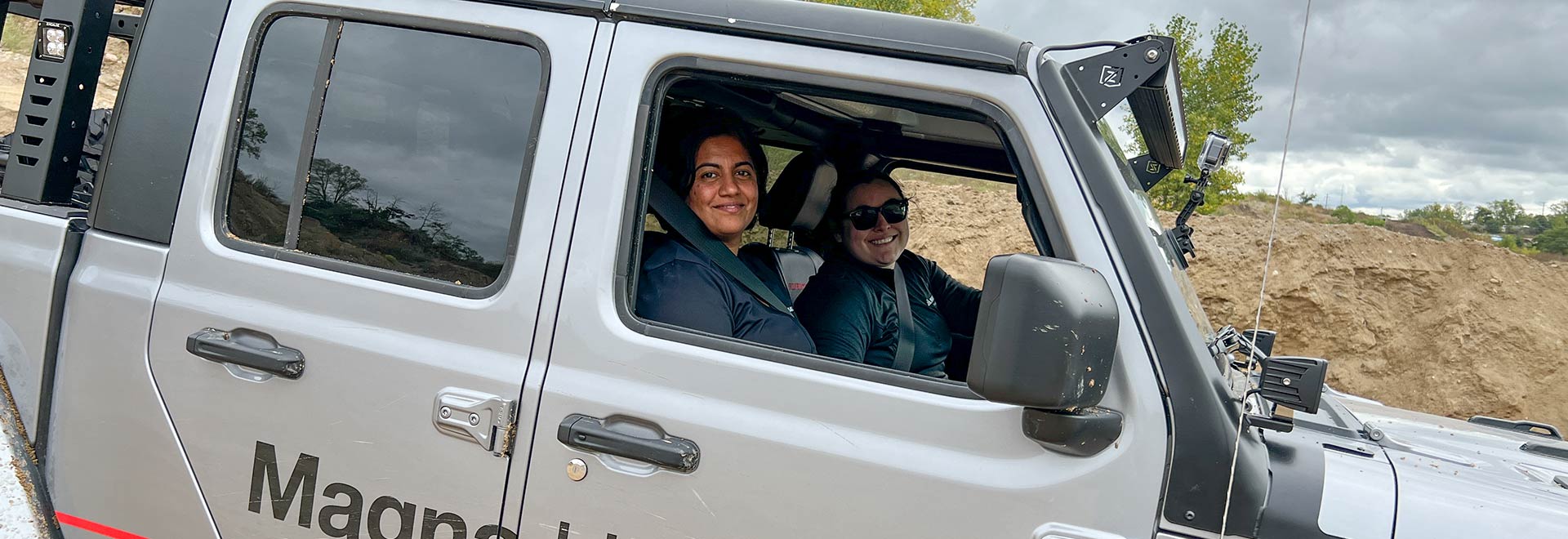 Two people sitting inside a Jeep Replicon in rugged terrain