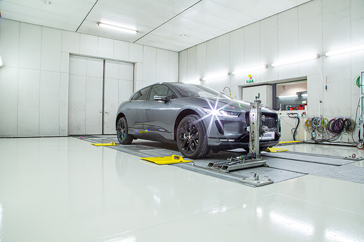 Grey vehicle attached to a 4WD Chassis Dynamometer in a manufacturing facility