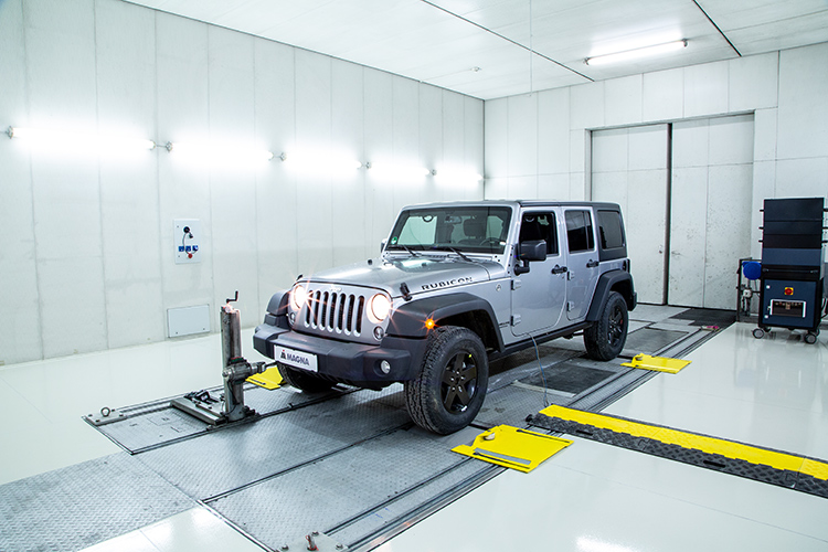Grey Jeep Rubicon connected to a 4WD Chassis Dynamometer in a manufacturing facility