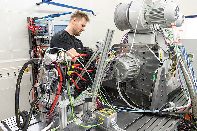 Person working on an eDrive testing machine in a manufacturing facility