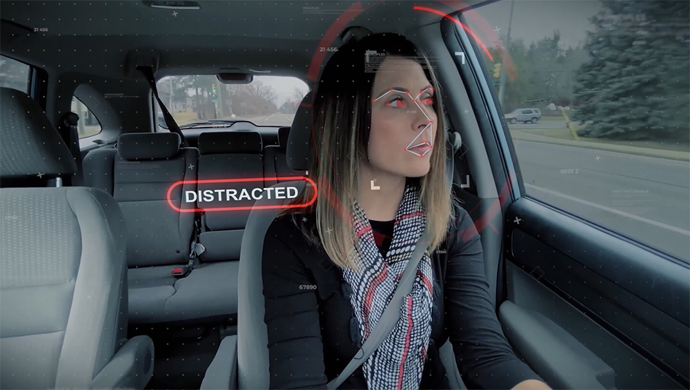 Person sitting in a vehicle illustrating distracted driving with interior sensing system