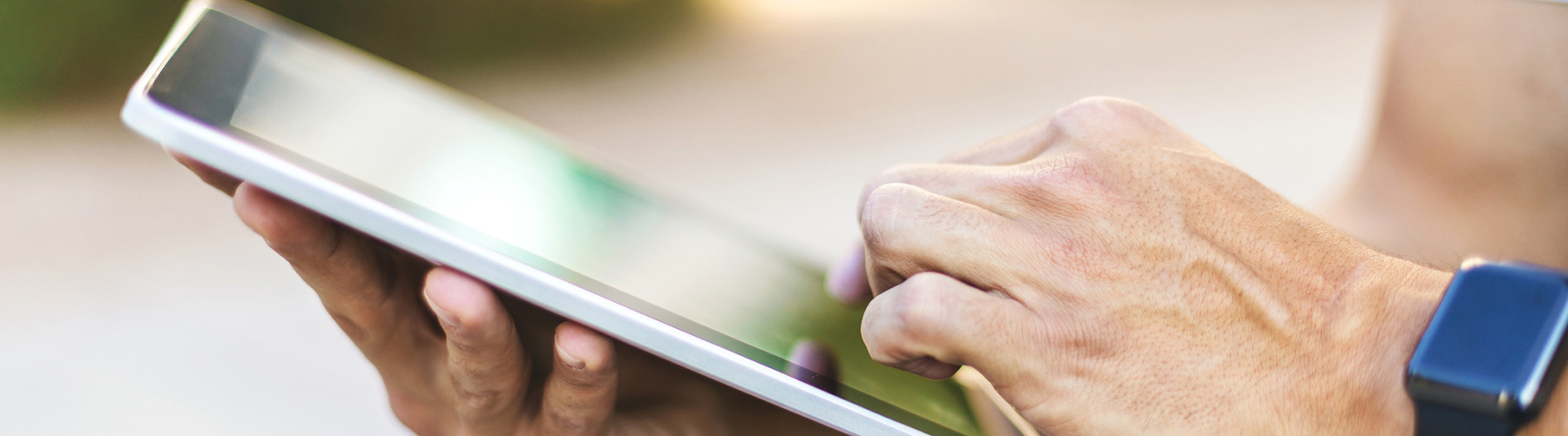 Person tapping on a tablet outside