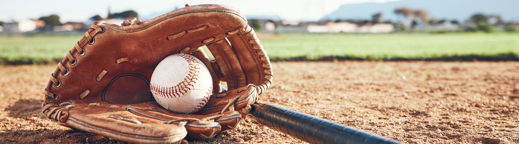 Baseball glove with a baseball and bat on a baseball diamond