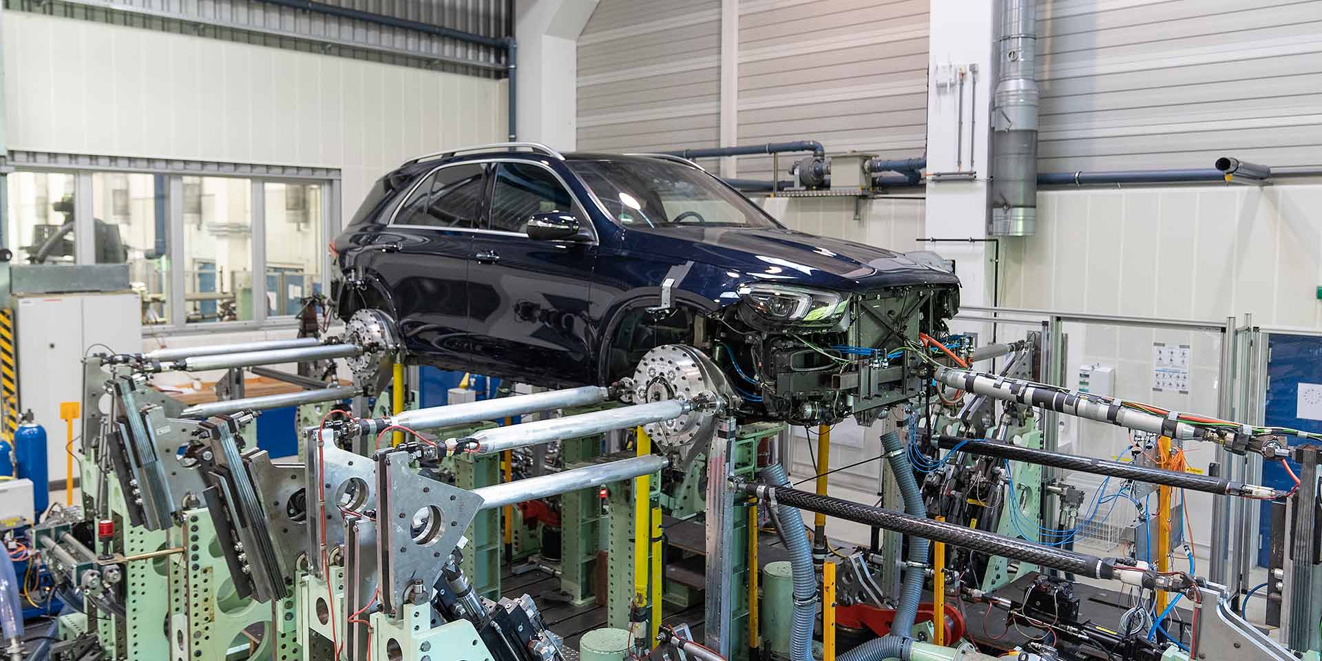 Autokarosserie auf einer Montagelinie, umgeben von Metallvorrichtungen und Maschinen.