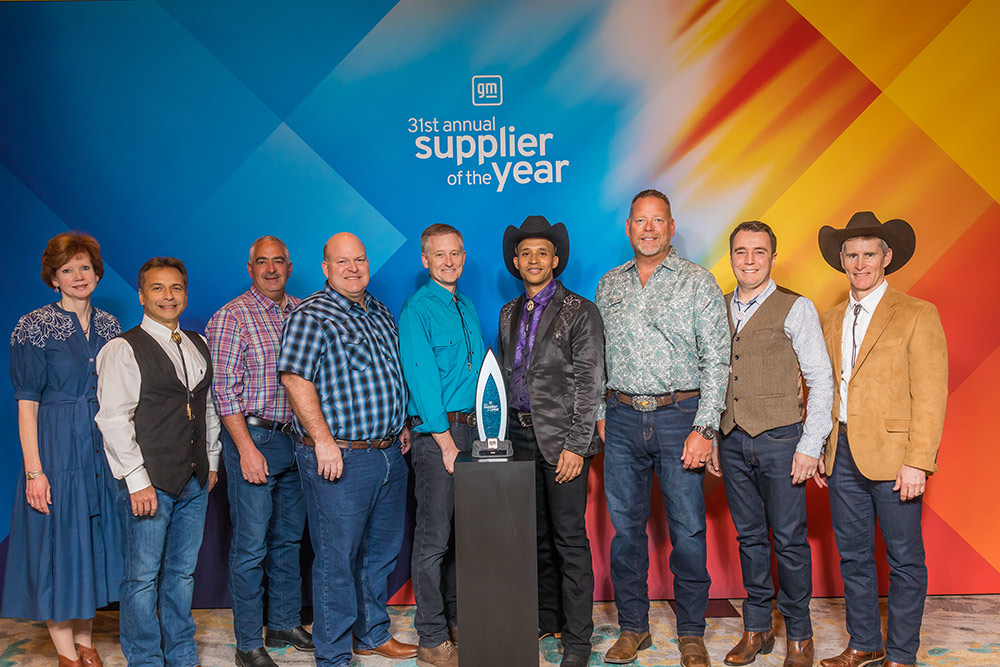 Group of people standing in front of the 2022 General Motors Supplier of the Year award