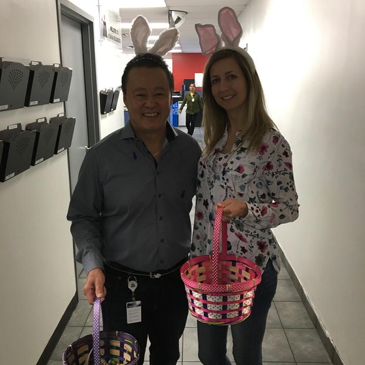 Adriana Huntington and coworker wearing bunny ears and carrying easter baskets in a hallway