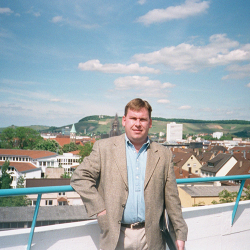 Doug Plester in a city in Germany with house and mountains in the background
