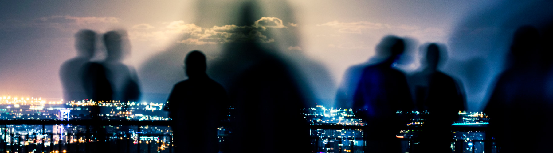 Silhouette of people in the foreground with city lights in the background