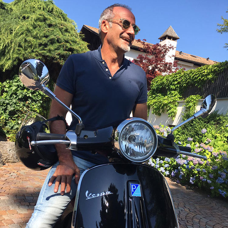 Stephan Baumann sitting on his black Vespa