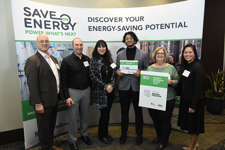 Ehson Ameer with a group of people standing in front of a poster receiving Save on Energy Award