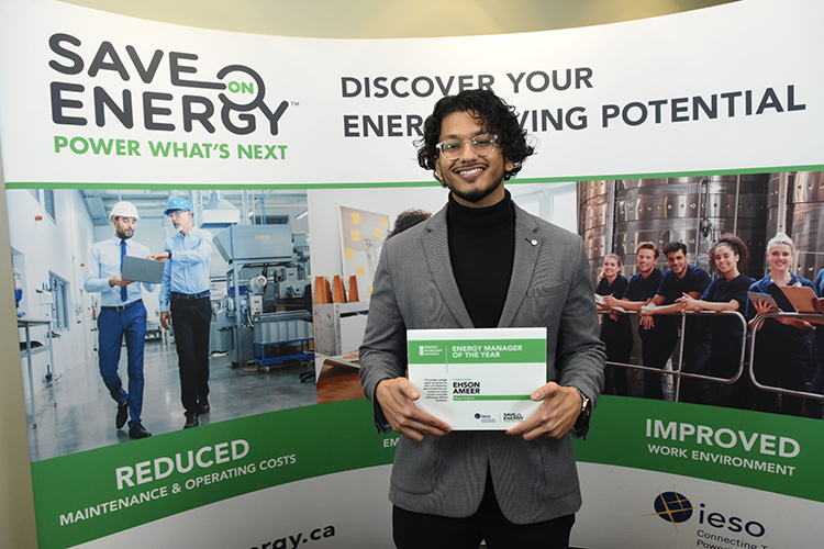 Ehson Ameer standing in front of a poster receiving Save on Energy Award