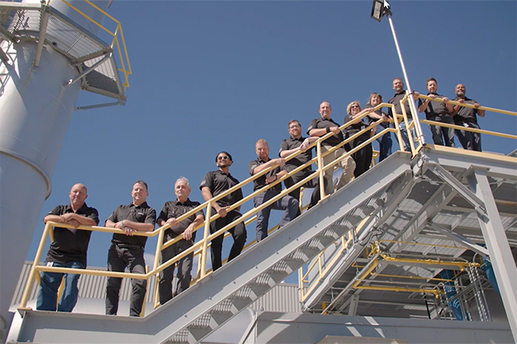 Group of people standing on stairs outside of a manufacturing plant