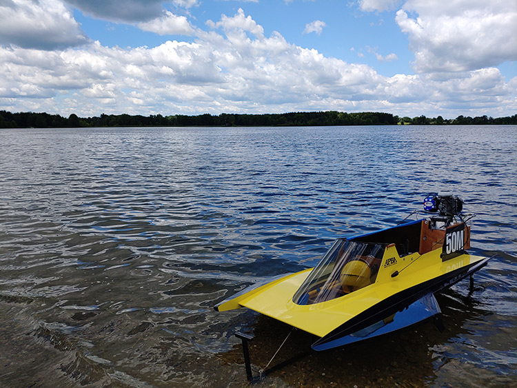 Yellow racing boat anchored to the shore of a lake