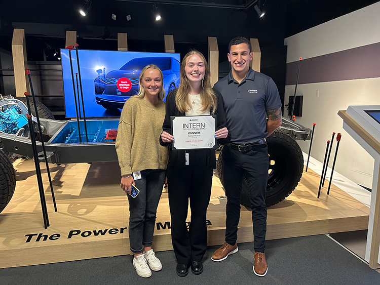 Katelyn Mitchell standing with two other people and holding a certificate