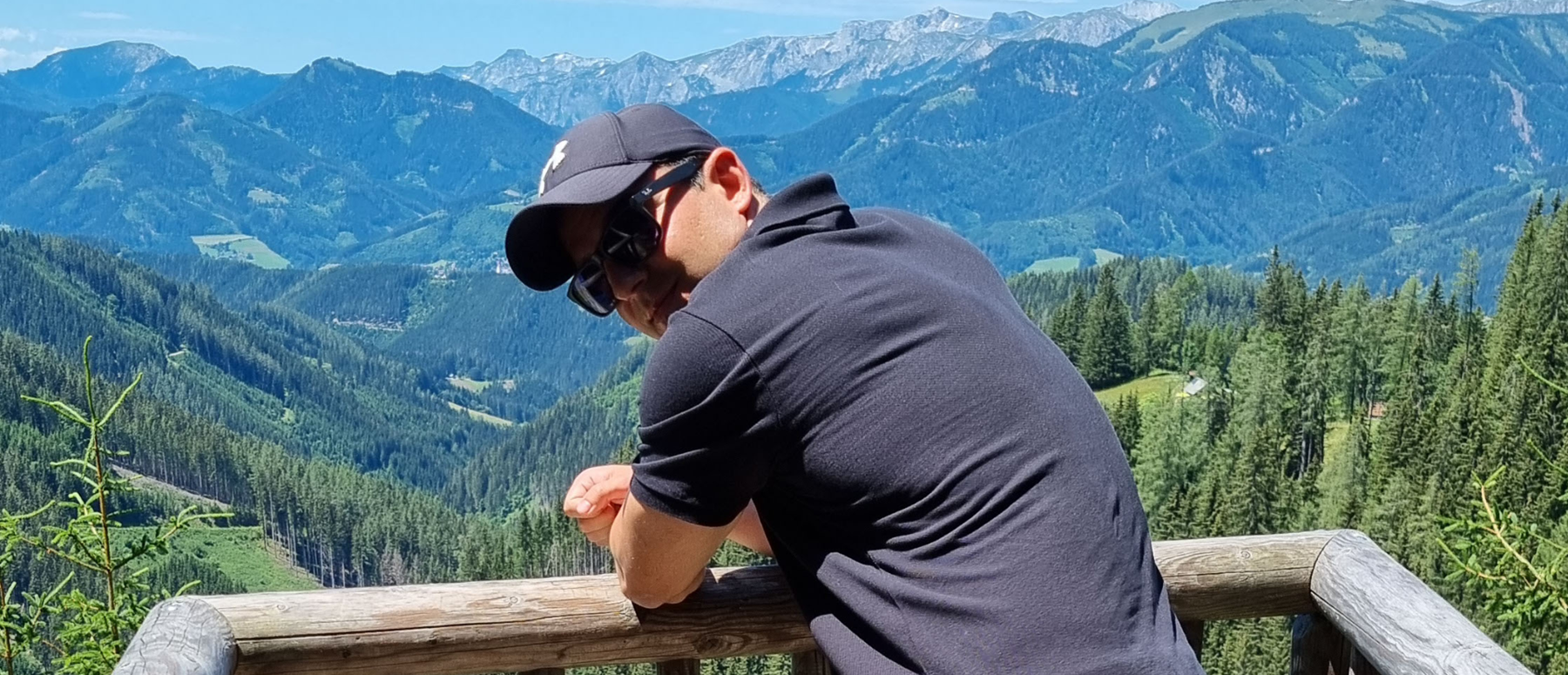 Tamas Meszaros standing on a bridge with mountains in the background