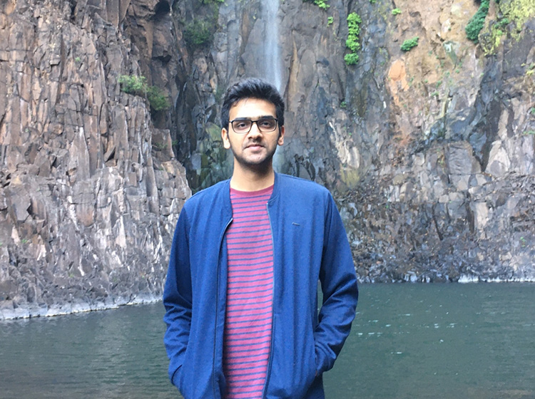 Nischay Hiremath standing in front of a waterfall