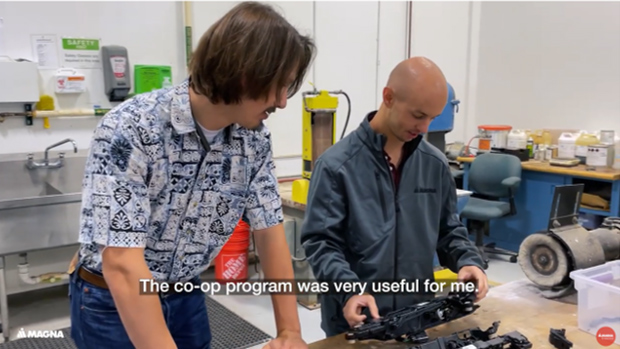 Two people working in a manufacturing facility on an automotive part