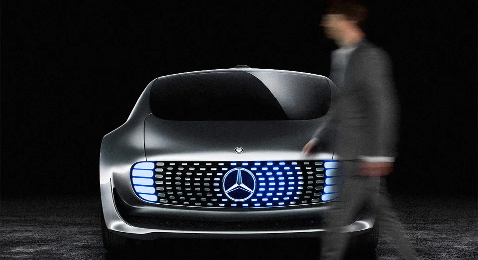 Blurred person walking in front of a grey Mercedes vehicle